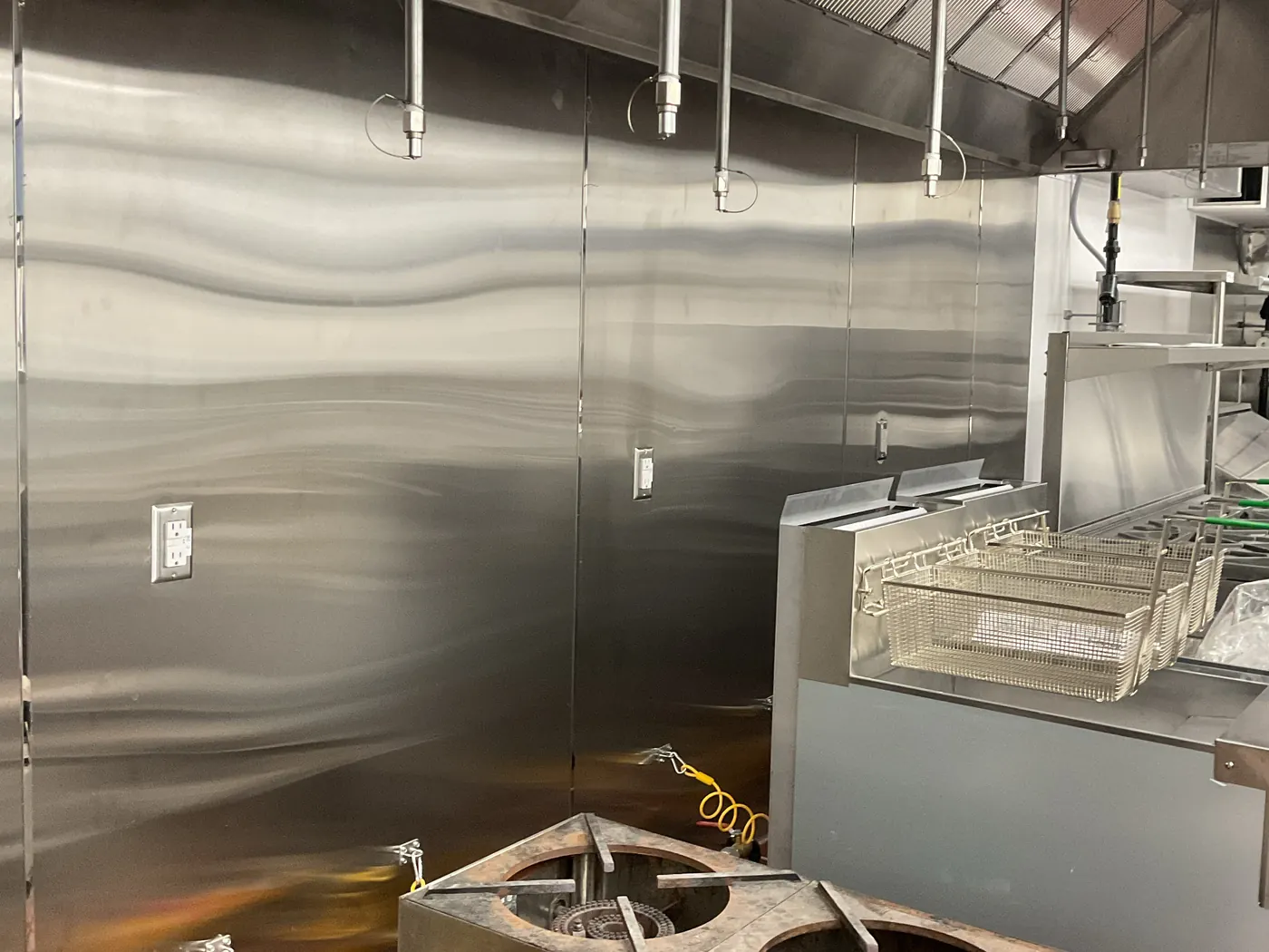 Finished kitchen cooking line with wok burners, a fryer, a stainless backsplash and a hood at the Lime & Lemon restaurant in Rolesville, NC