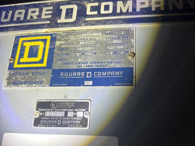 Close-up of the manufacturer nameplate and listing label on a gray switchboard section