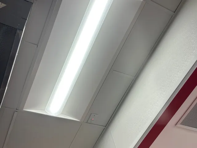 Single long LED troffer fixture lit in a white drop-ceiling grid